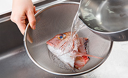 鯛のあらは熱湯をかけて霜降りし、ウロコをキレイにこそげ取る。